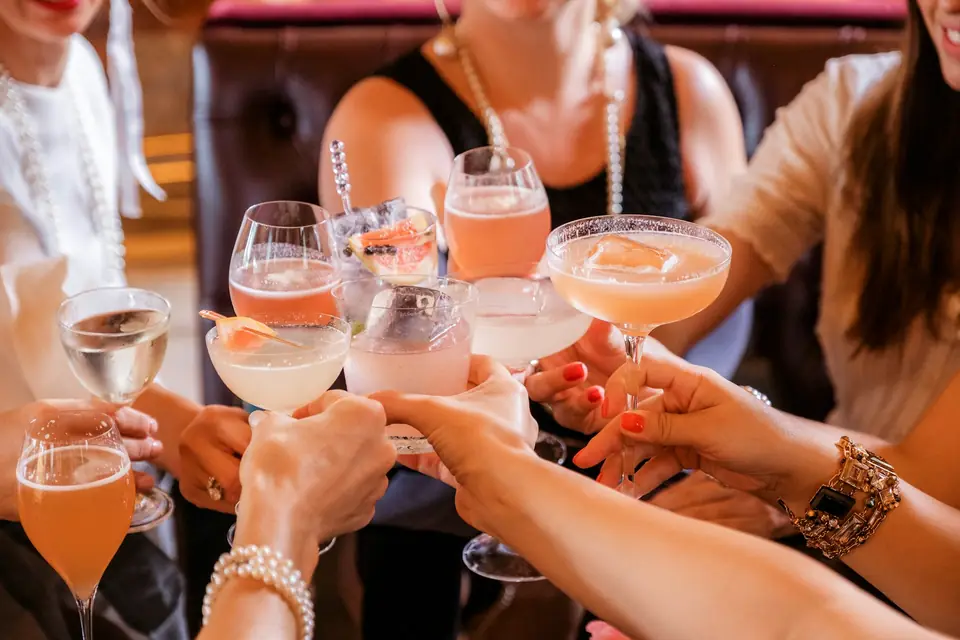 Friends raising pink cocktails together in a toast