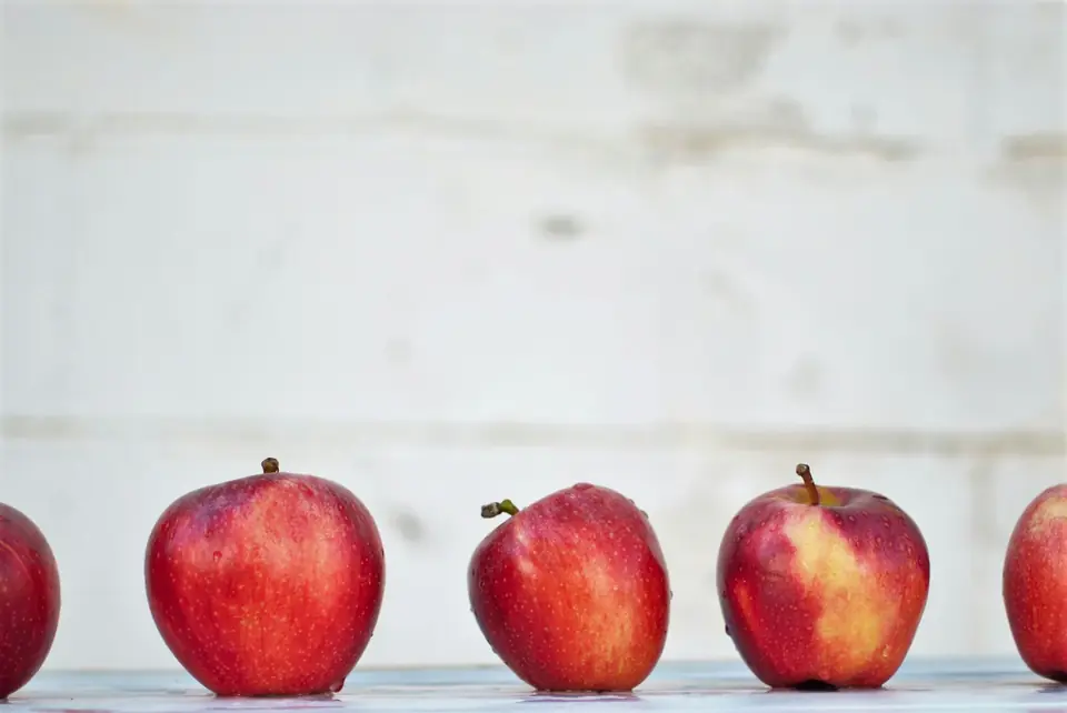 Red apples lined up on a white table