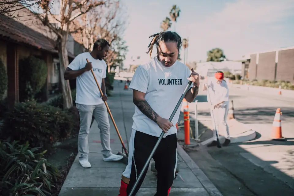Volunteers in T-shirts sweeping a neighborhood street