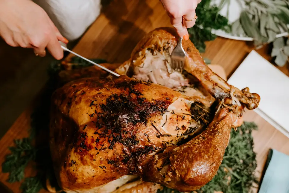 A whole roast bird being carved on a wooden board